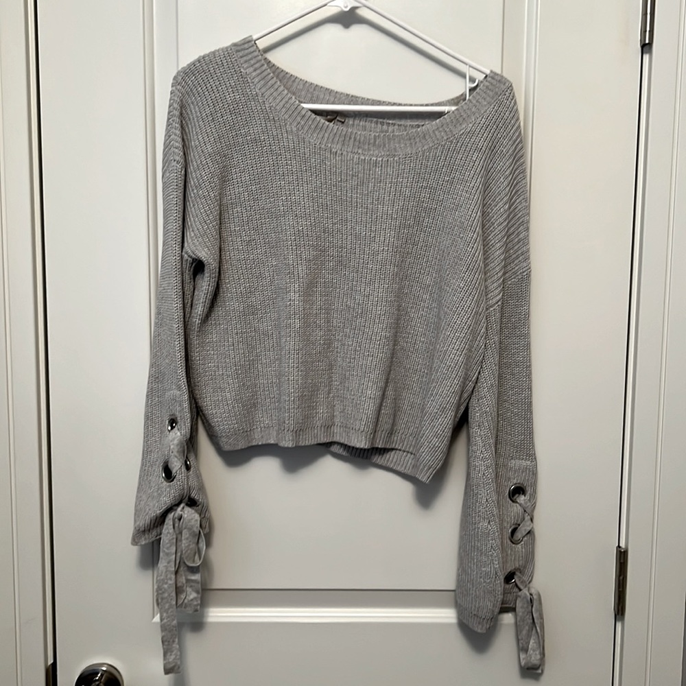 Oversized gray sweater with tie details at the wrist.
